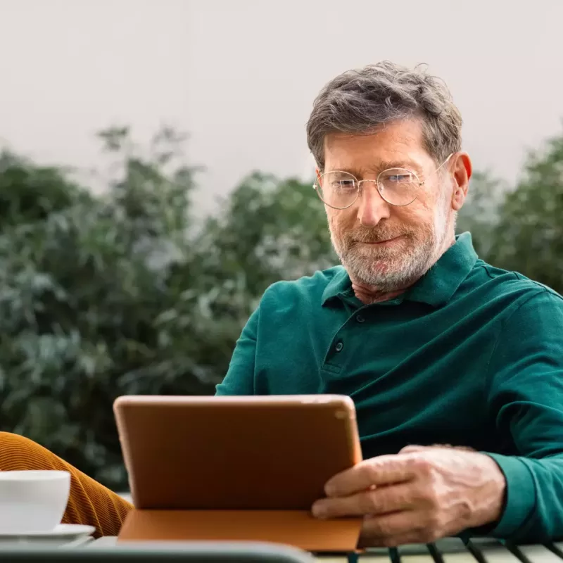 man sitting at table looking at a tablet screen