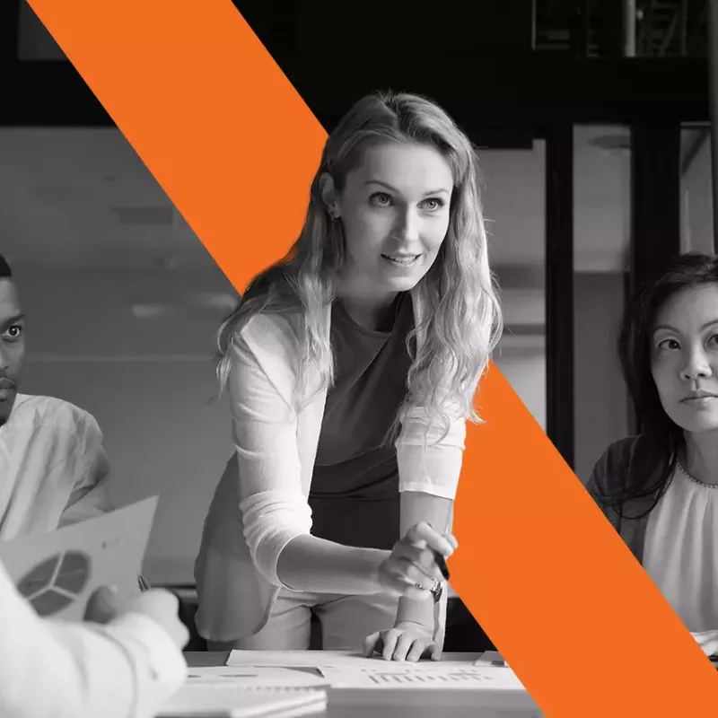 black and white woman leaning over table around a group of people blog header for Xactly