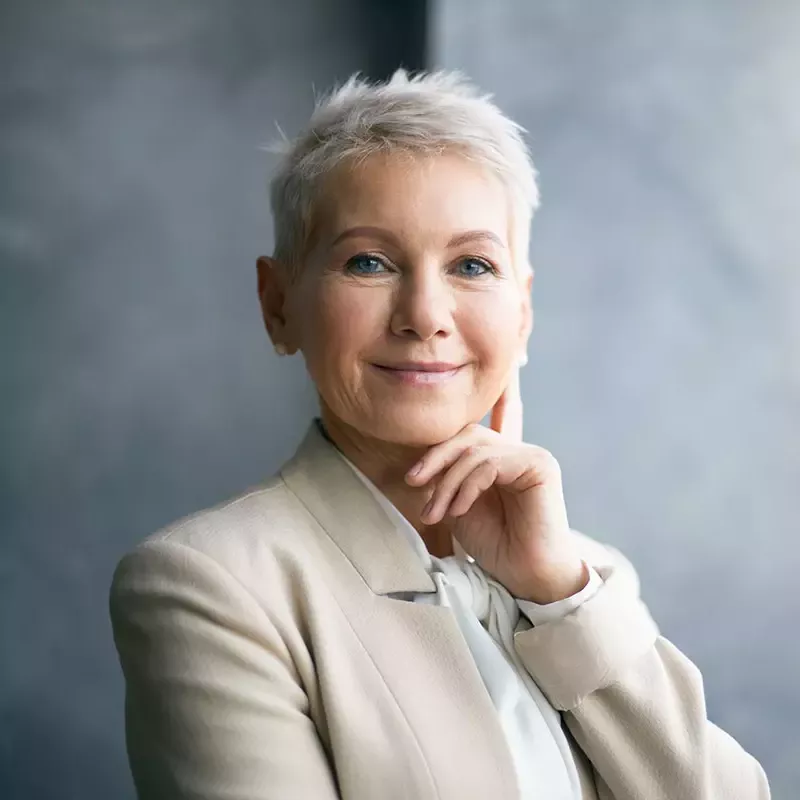 White-haired woman in a business suit exuding confidence.