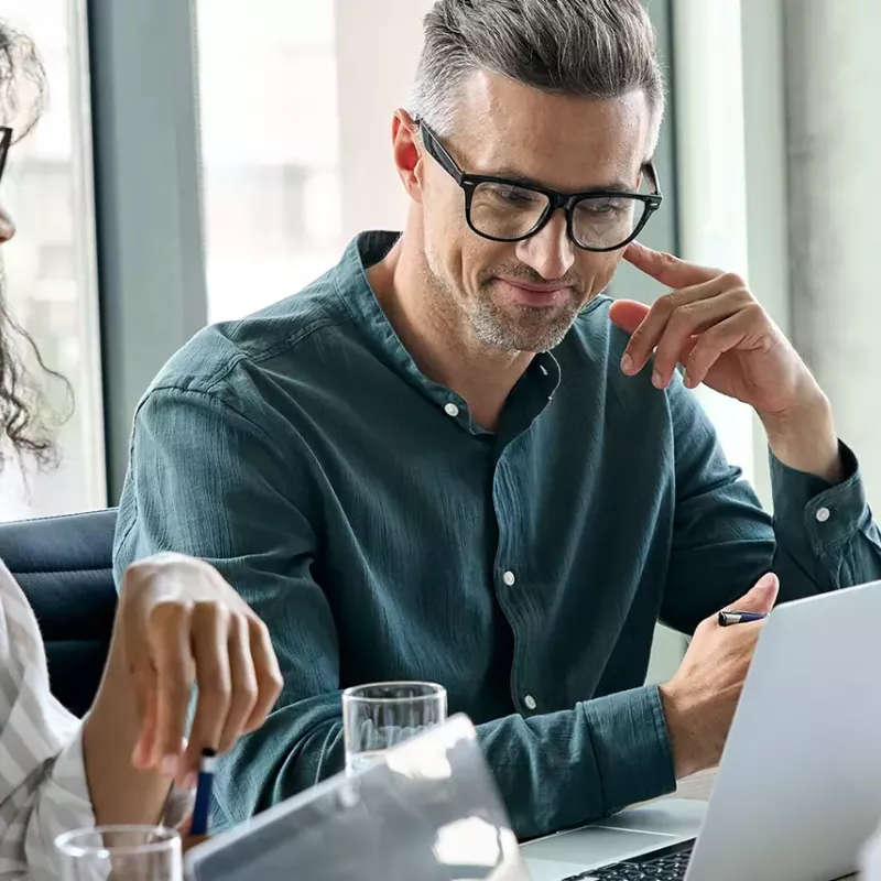 man with glasses sitting in front of computer thinking 