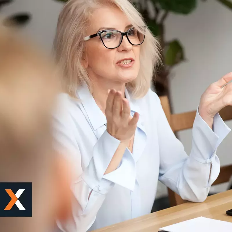 Woman speaking to a group of salespeople sitting around a table