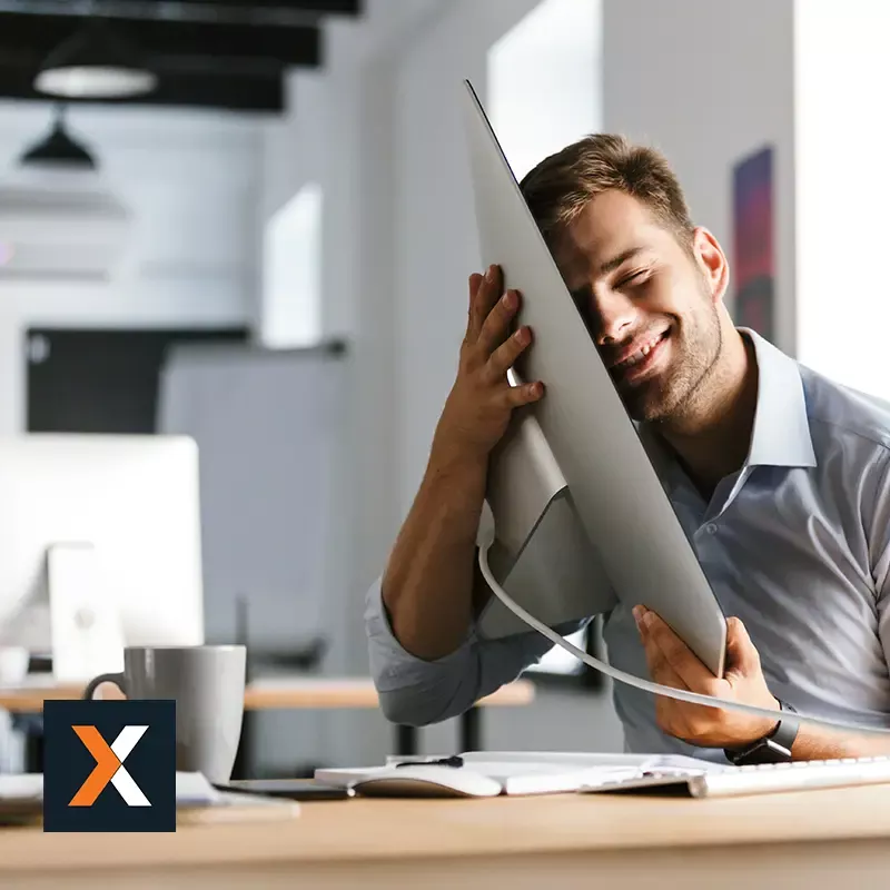 man sitting at desk hugging compuetr