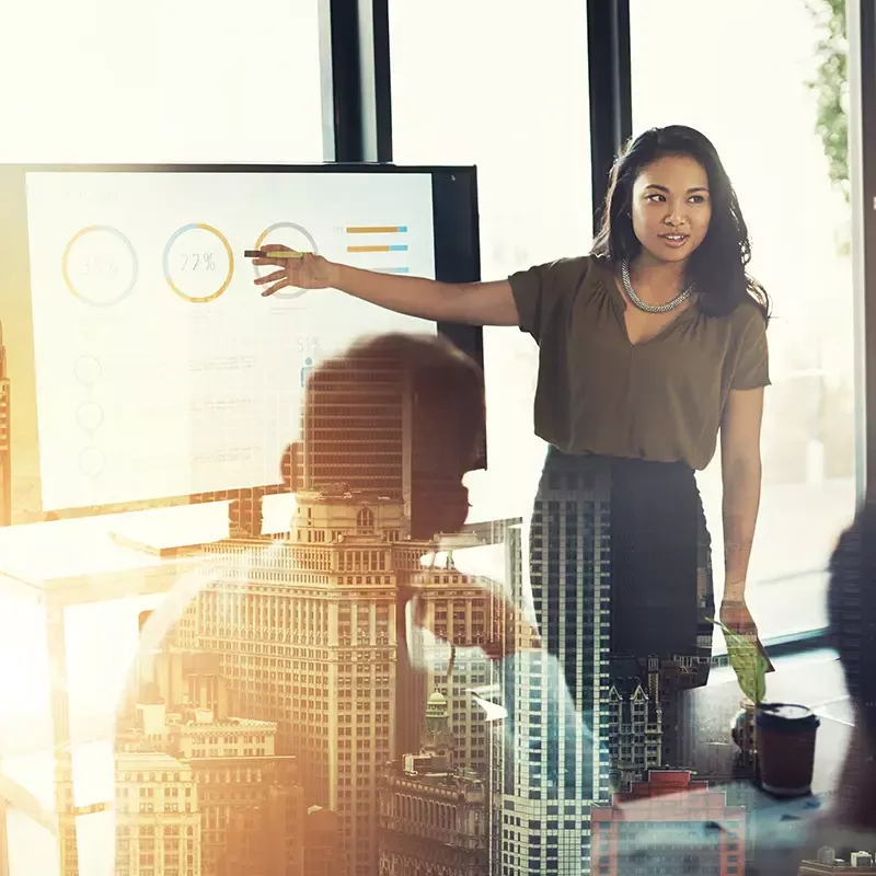 Woman standing presenting at monitor to a group of people