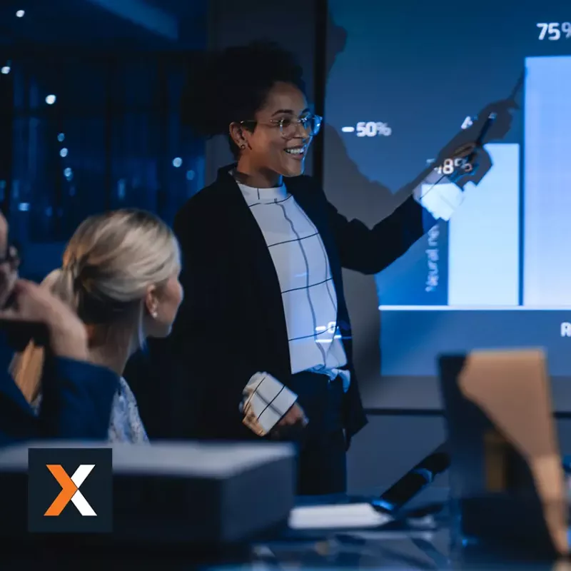 Woman standing at digital whiteboard presenting to a group of business professionals