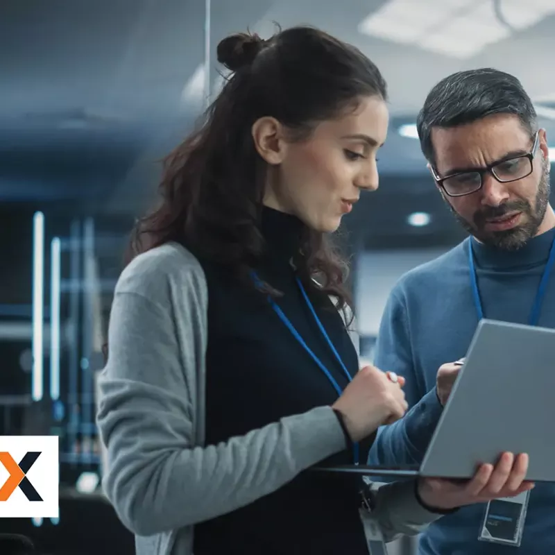 Woman and man standing next to each other looking at laptop together