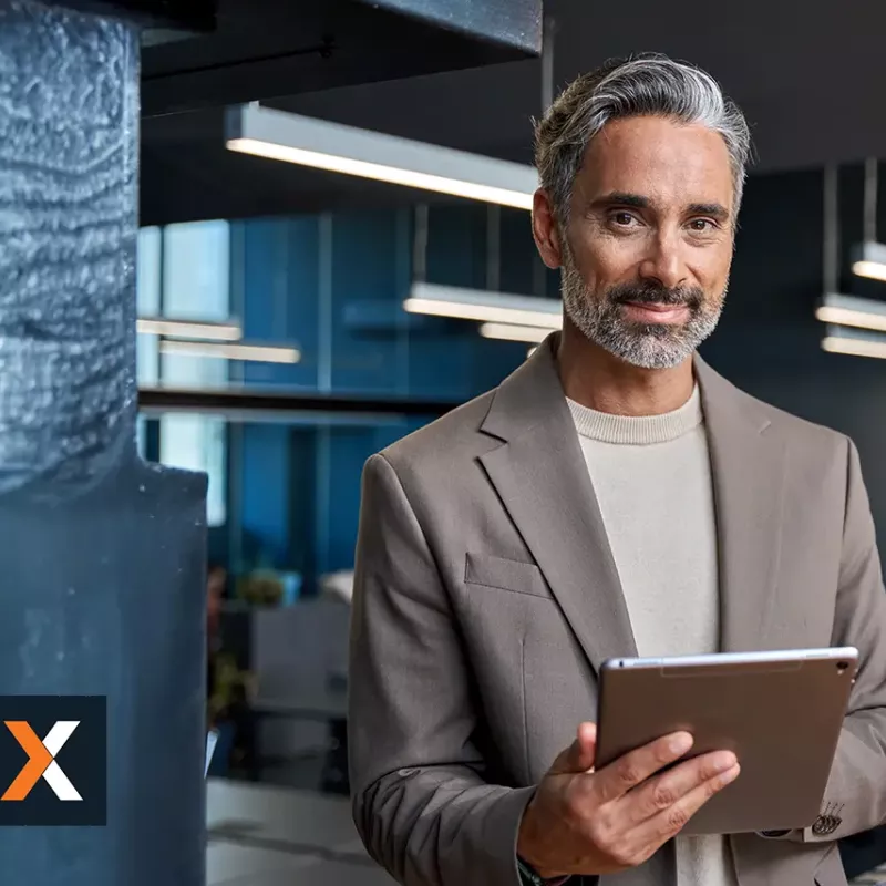 Businessman standing working off tablet smiling at camera