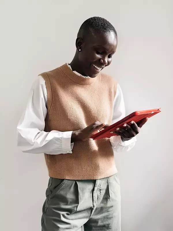 A tech-savvy woman in casual clothing confidently holds a tablet in her hands.