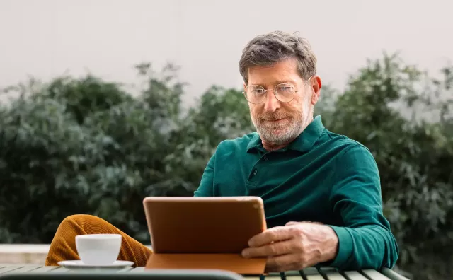 man sitting at table looking at a tablet screen