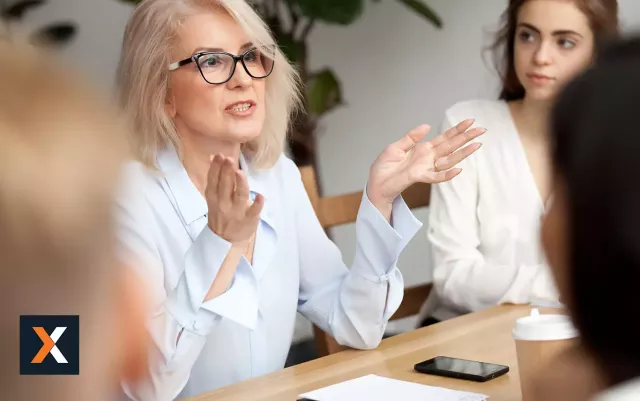 Woman speaking to a group of salespeople sitting around a table