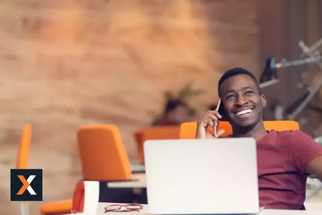 man sitting at desk with laptop facing camera smiling