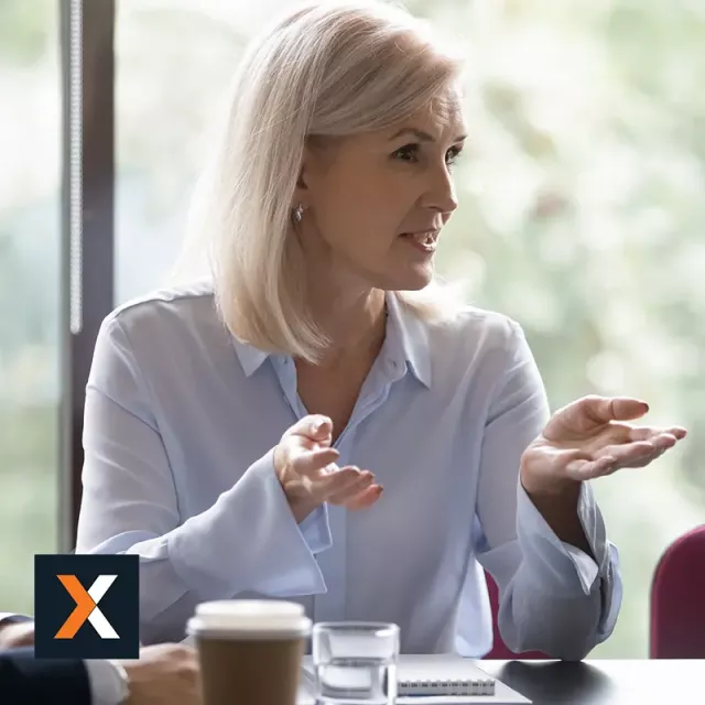 Business woman sitting at table speaking to other business professionals