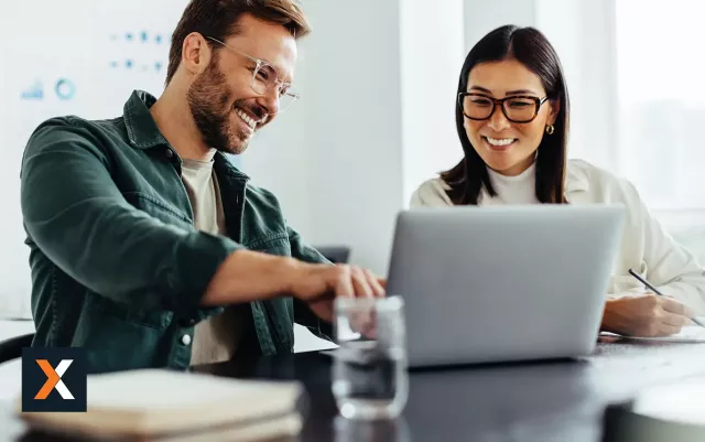 Man and woman working off the same laptop together smiling