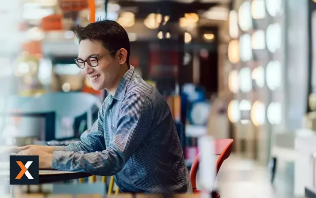 man with glasses smiling working at computer