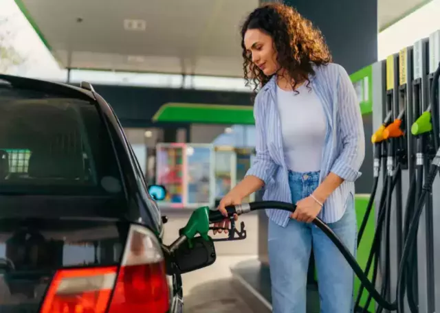 A young woman puts fuel in her car at gas station.